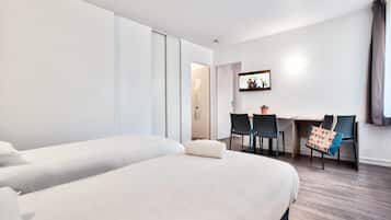 Een hotelkamer met twee bedden, een bureau en stoelen.