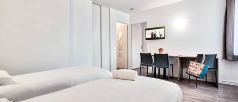Een hotelkamer met twee bedden, een bureau en stoelen.