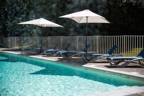 Una piscina al aire libre, tumbonas