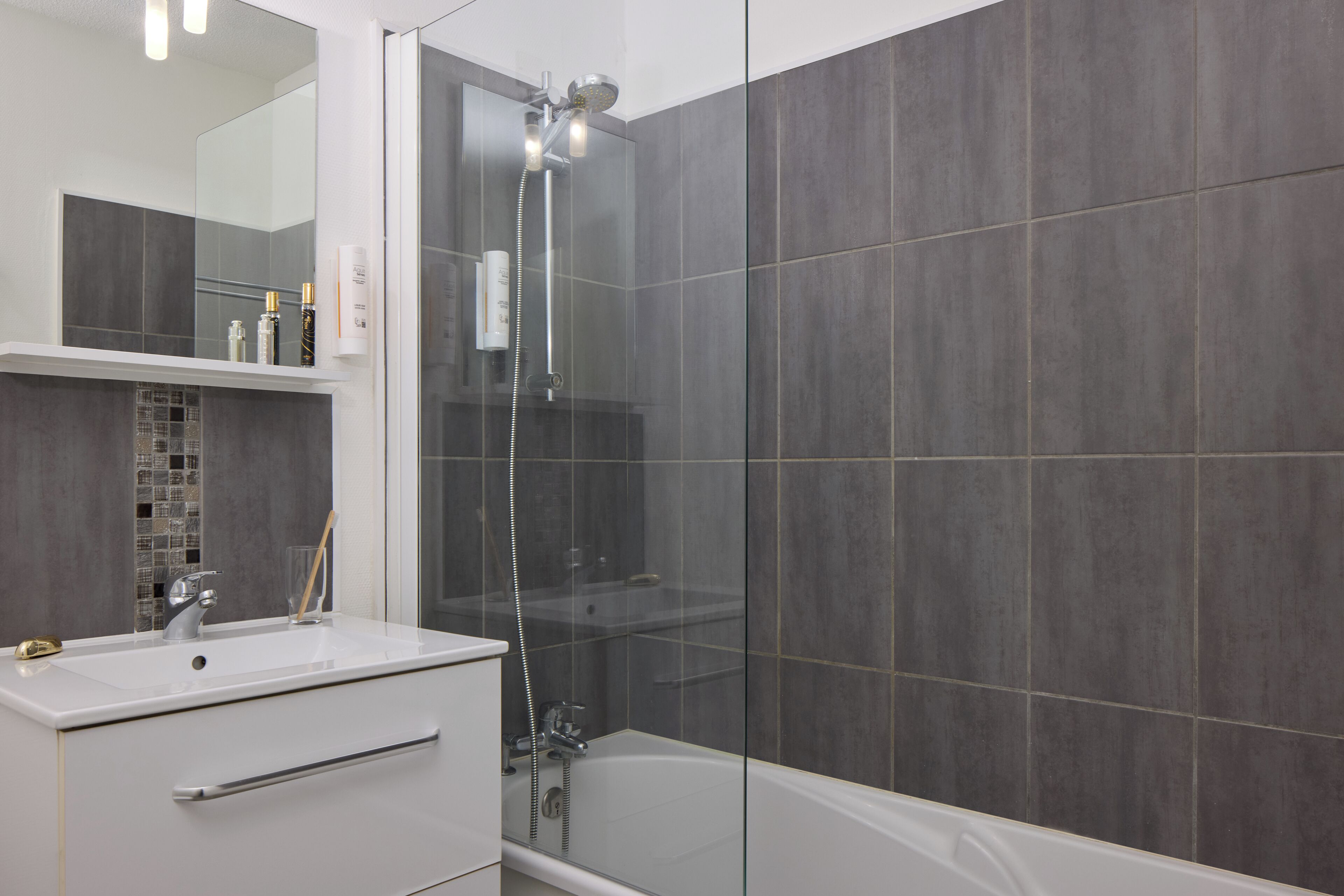 Un baño moderno con ducha envuelta en vidrio, un lavabo blanco y una bañera.