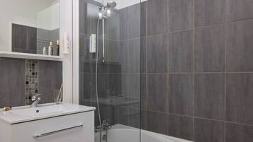 Un baño moderno con ducha envuelta en vidrio, un lavabo blanco y una bañera.