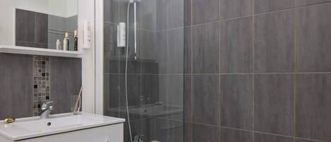 Ein modernes Badezimmer mit einer gläsernen Duschkabine, einem weißen Waschbecken und einer Badewanne.