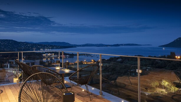 A terrace with wicker chairs and a table, overlooking a body of water and distant hills. - Hotel Alcyon Porto Vecchio (Porto-Vecchio)