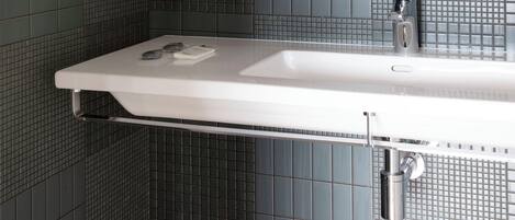 A bathroom with a white sink, a mirror, and a tiled wall.