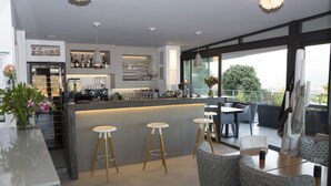 A modern kitchen with a bar area, bar stools, and a dining area with a table and chairs. - Hotel Alcyon Porto Vecchio (Porto-Vecchio)