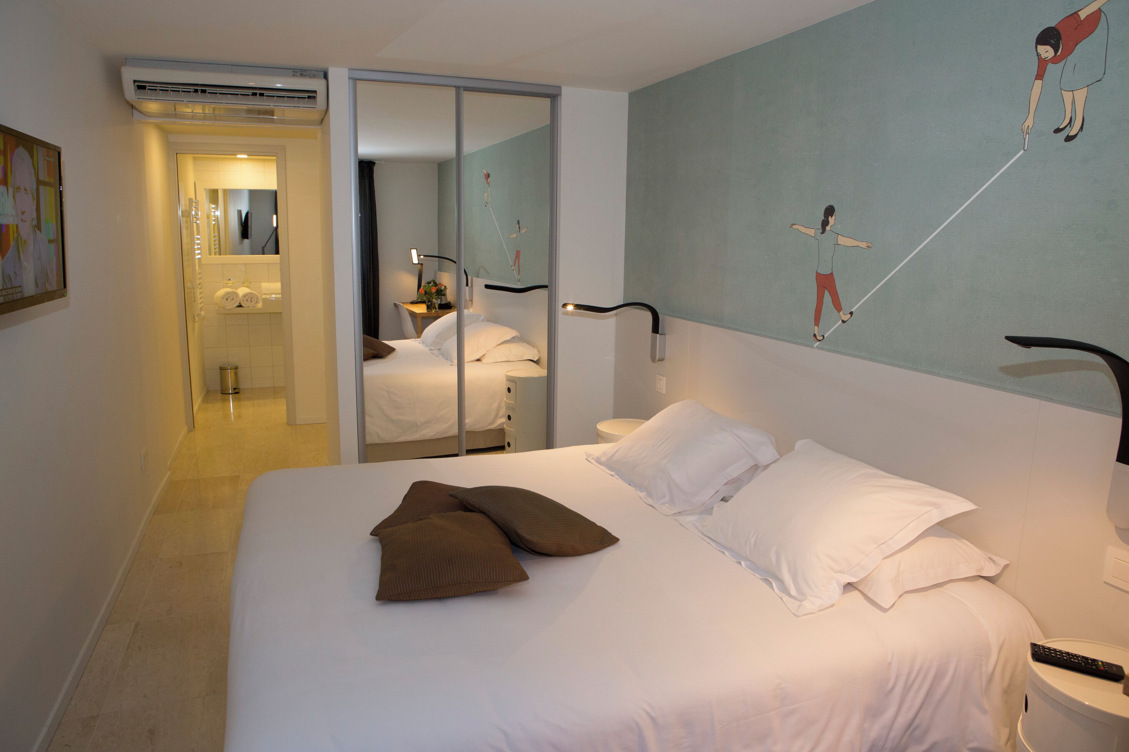 Quarto de hotel com cama, banheiro com espelho e parede com quadro.