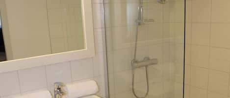 A bathroom with a glass-enclosed shower, a white sink, and a mirror above the sink.
