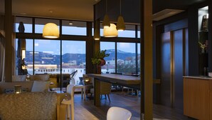 A modern interior with large windows, a dining area, and a view of a cityscape. - Hotel Alcyon Porto Vecchio (Porto-Vecchio)