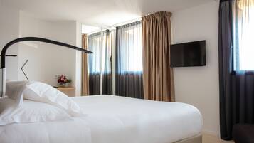 A hotel room with a bed, a TV, and curtains.