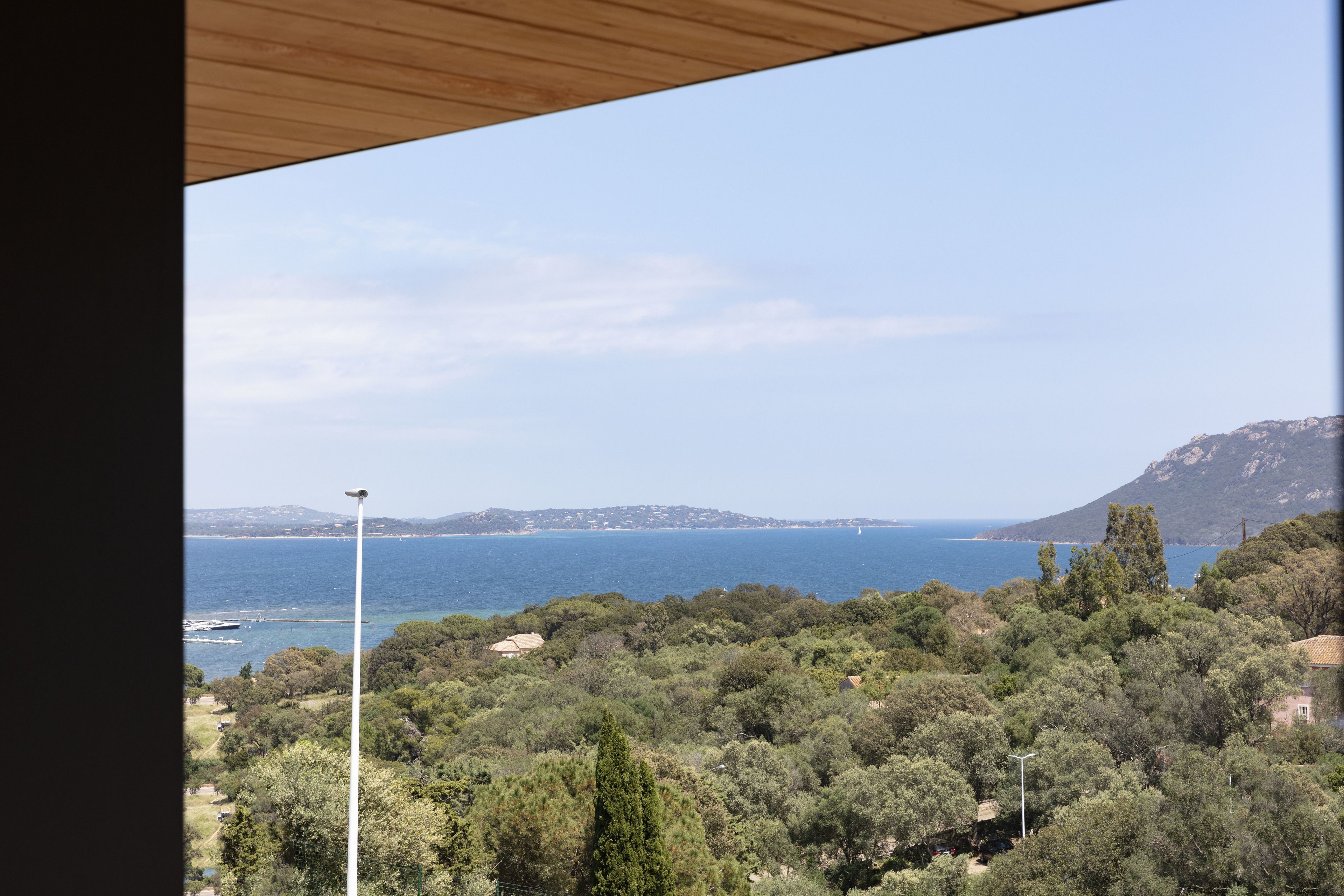 Eine Küstenlandschaft mit Blick auf das Meer, Bäume und ferne Hügel.