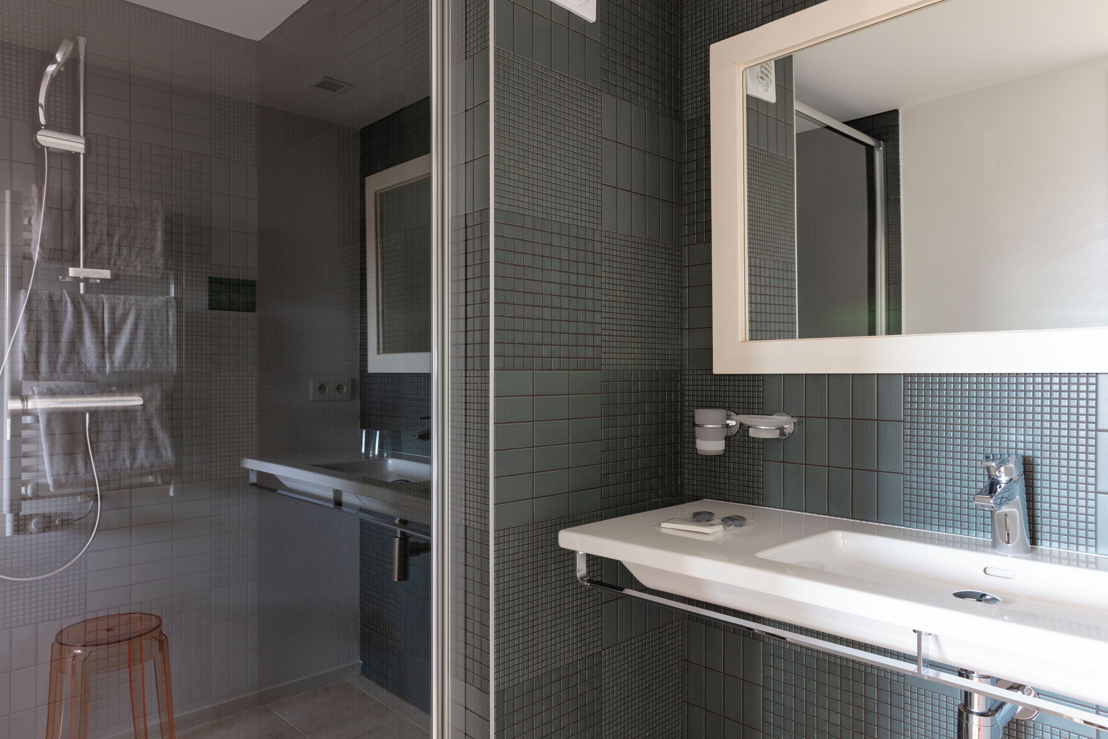 Un bagno moderno con box doccia in vetro, lavandino bianco e uno specchio grande.