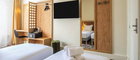 Une chambre d’hôtel avec deux lits, un bureau, une chaise, une télévision et un miroir.