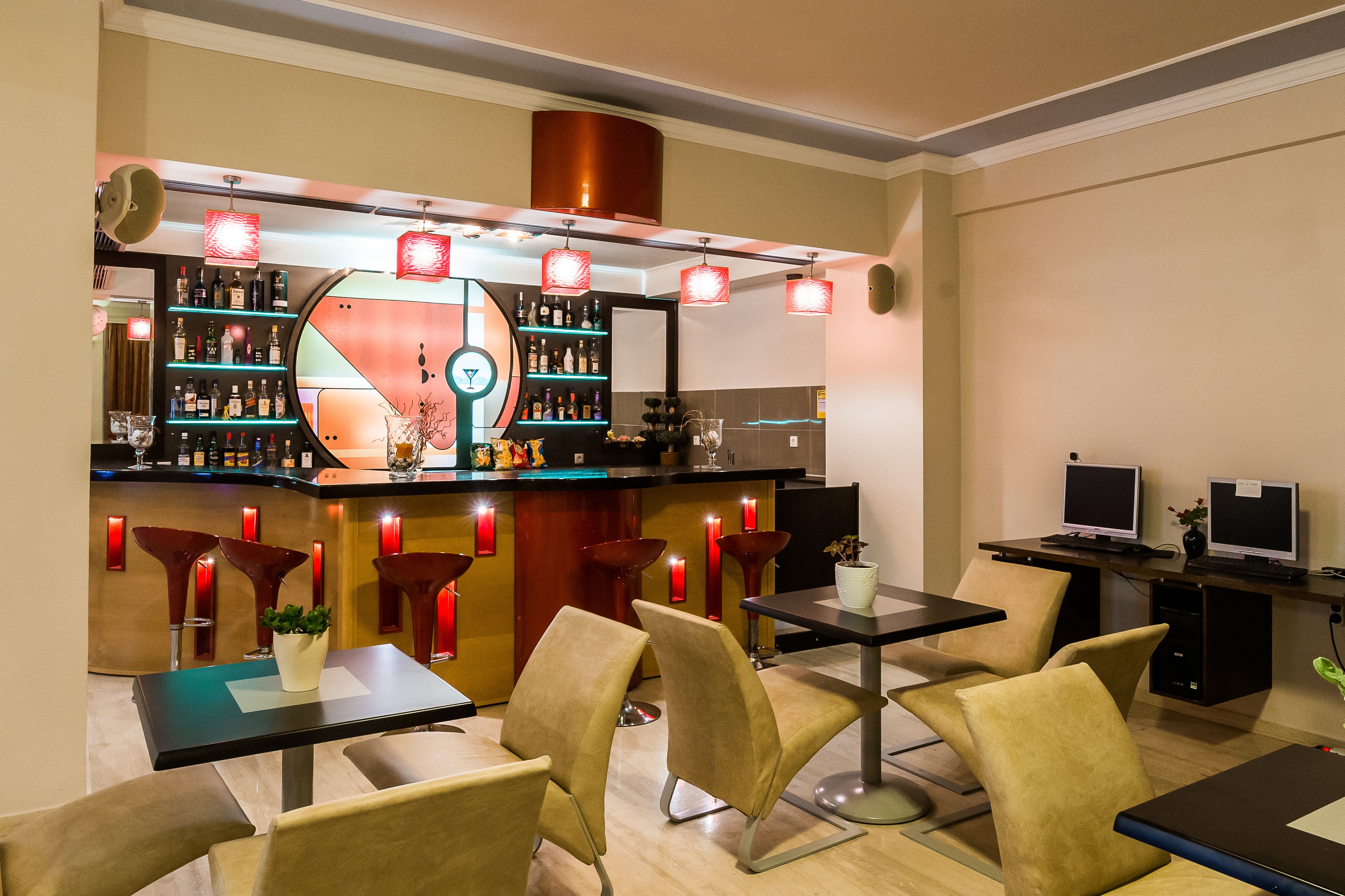 A modern bar area with a curved counter, multiple seating options, and a variety of bar tools and bottles.