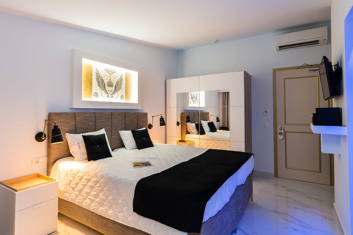 A modern bedroom with a large bed, bedside tables, a wardrobe, and a television.