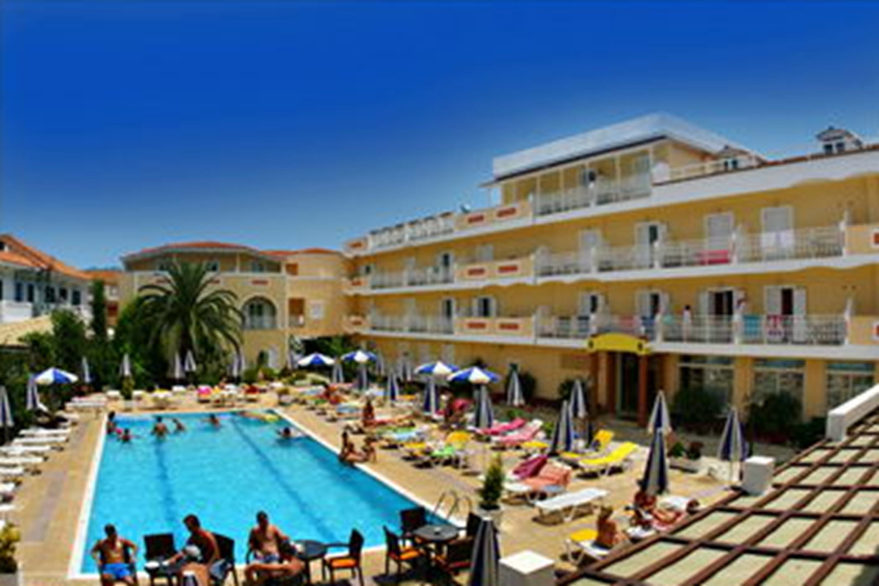 A pool area with multiple levels of balconies, sun loungers, and umbrellas.
