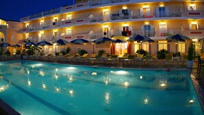 Ein Hotel mit Schwimmbad, Liegestühlen und Sonnenschirmen.