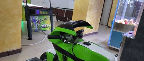 A green scooter with a black handlebar and a rear storage compartment.