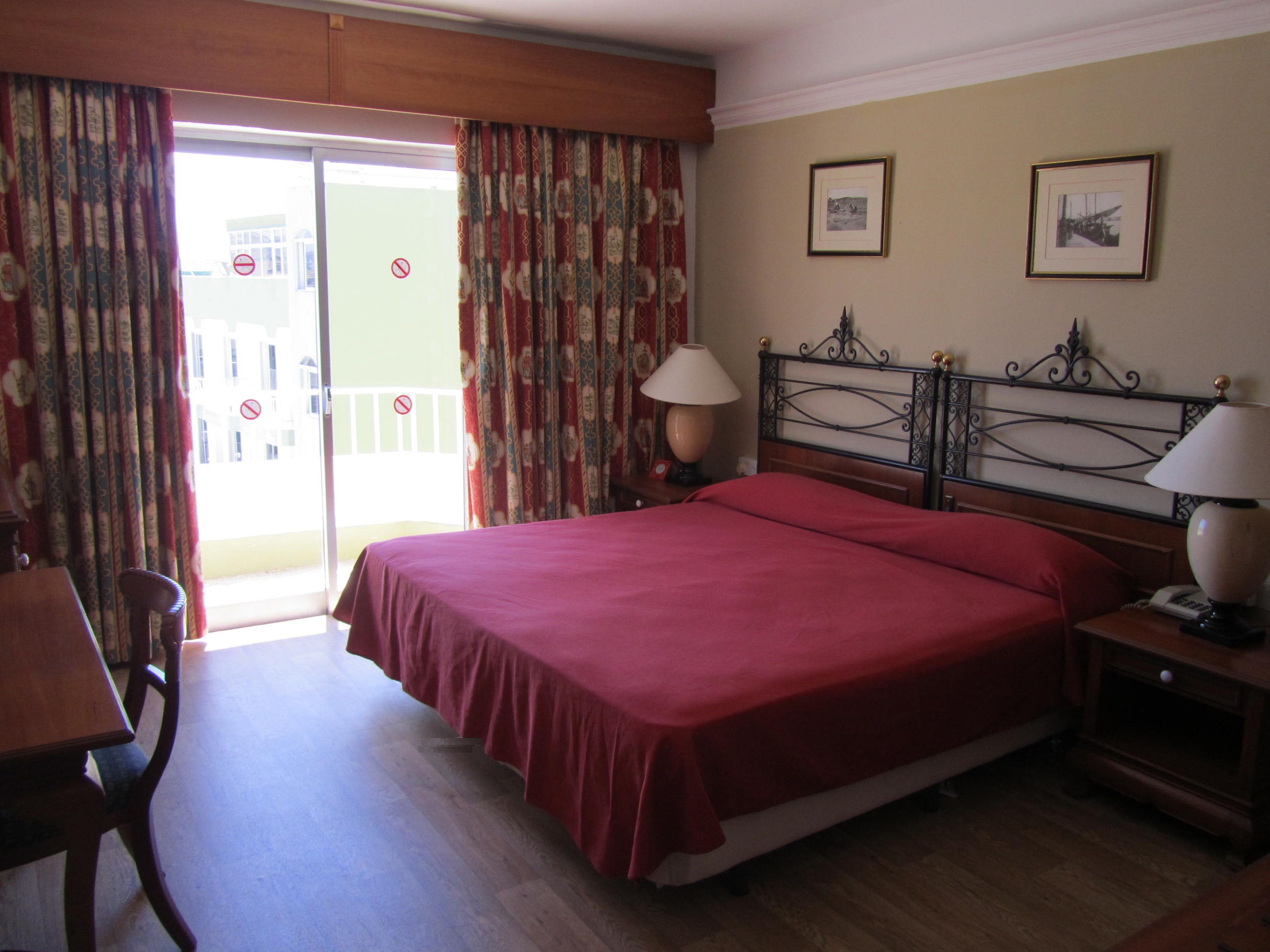 A hotel room with a bed, two bedside lamps, a chair, and a table.