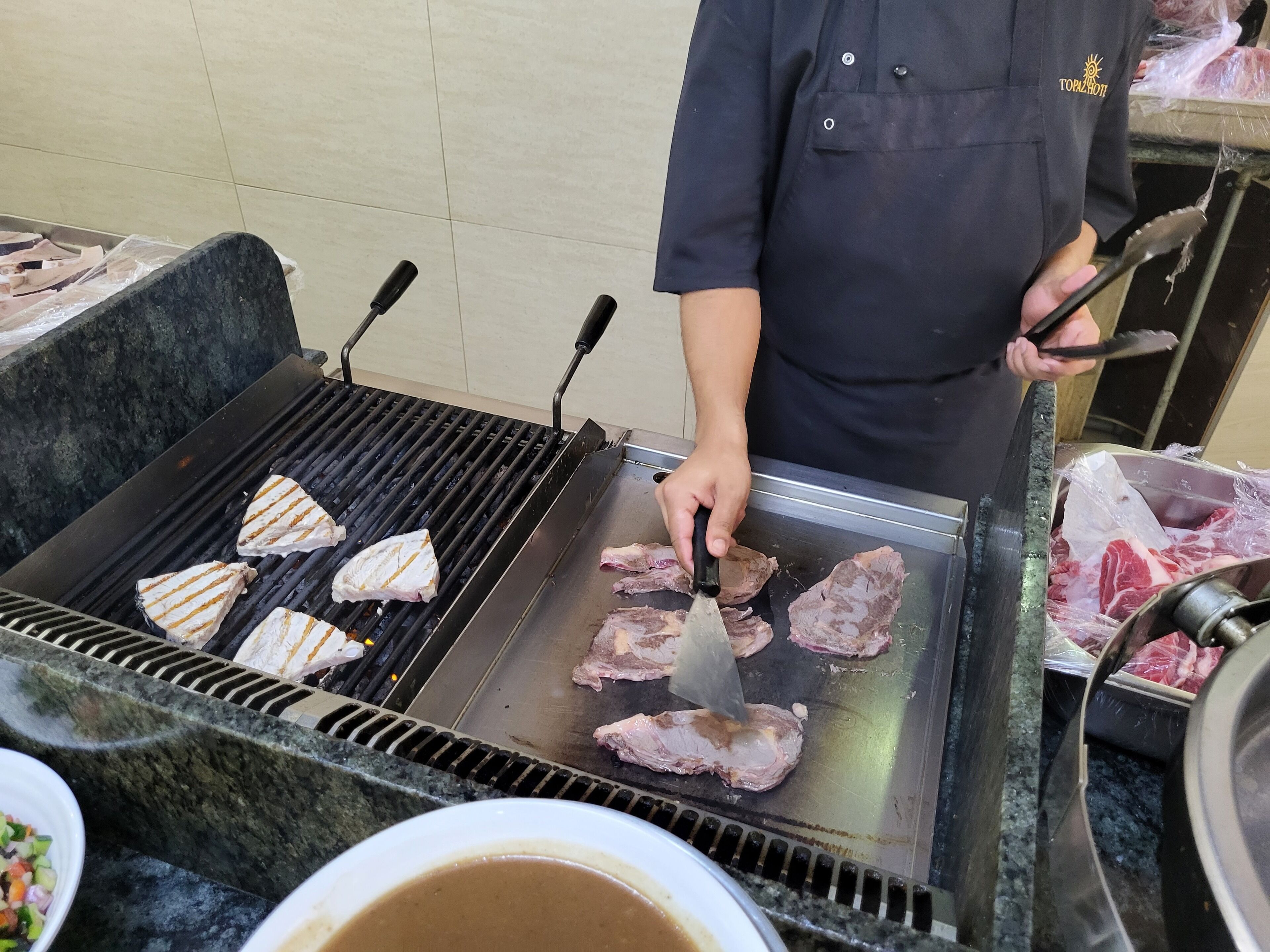 Una persona asando carne en una parrilla portátil.