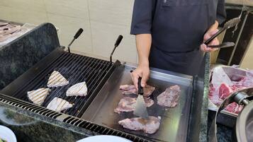 Una persona asando carne en una parrilla portátil.