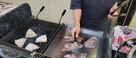 Una persona asando carne en una parrilla portátil.