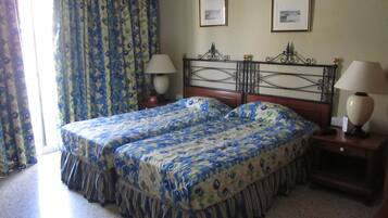 Una cama doble con ropa de cama floral, dos lámparas de noche y un cabecero con detalles de metal decorativo.