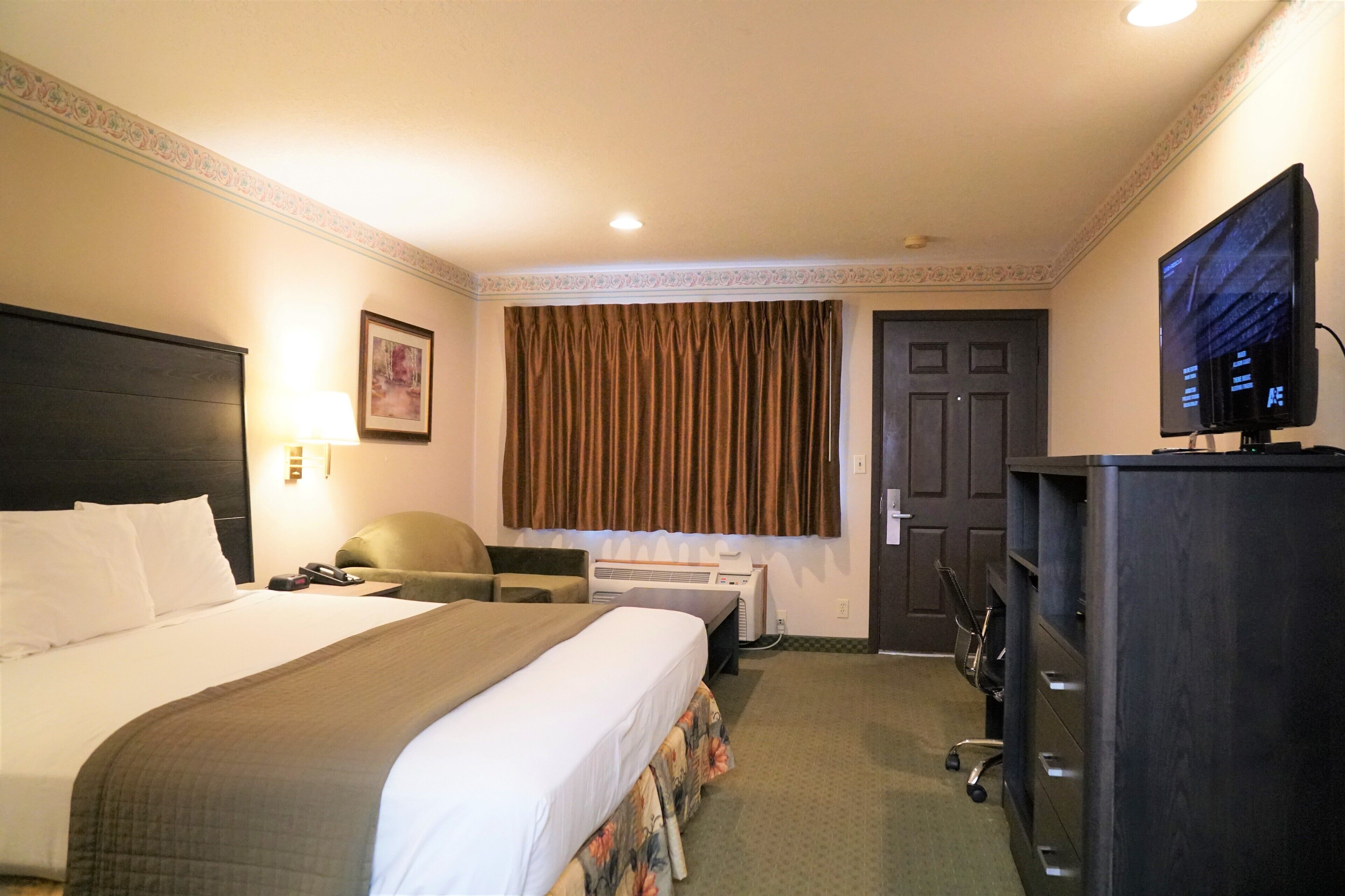 Une chambre d’hôtel équipée d’un lit, d’un bureau, d’une chaise, d’une télévision et d’une armoire.