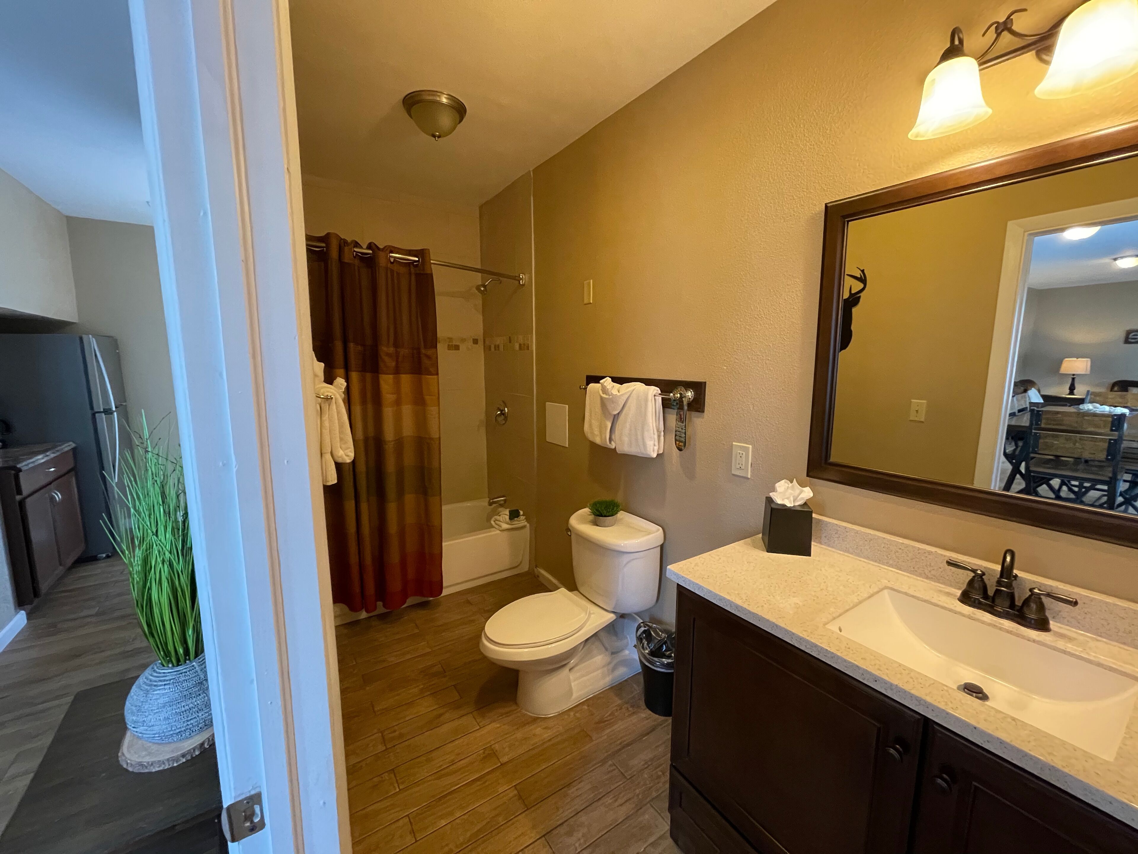 A bathroom with a shower, toilet, sink, and a mirror.
