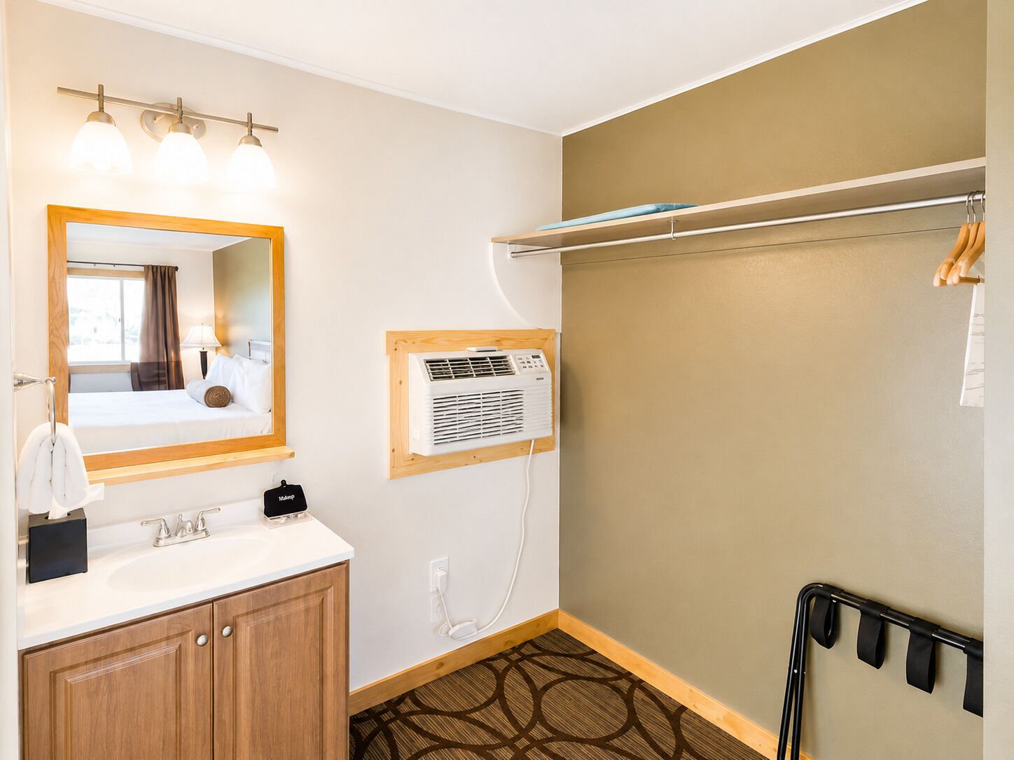 Un baño de hotel con espejo, tocador, perchero para toallas, ducha y dispensador de toallas.