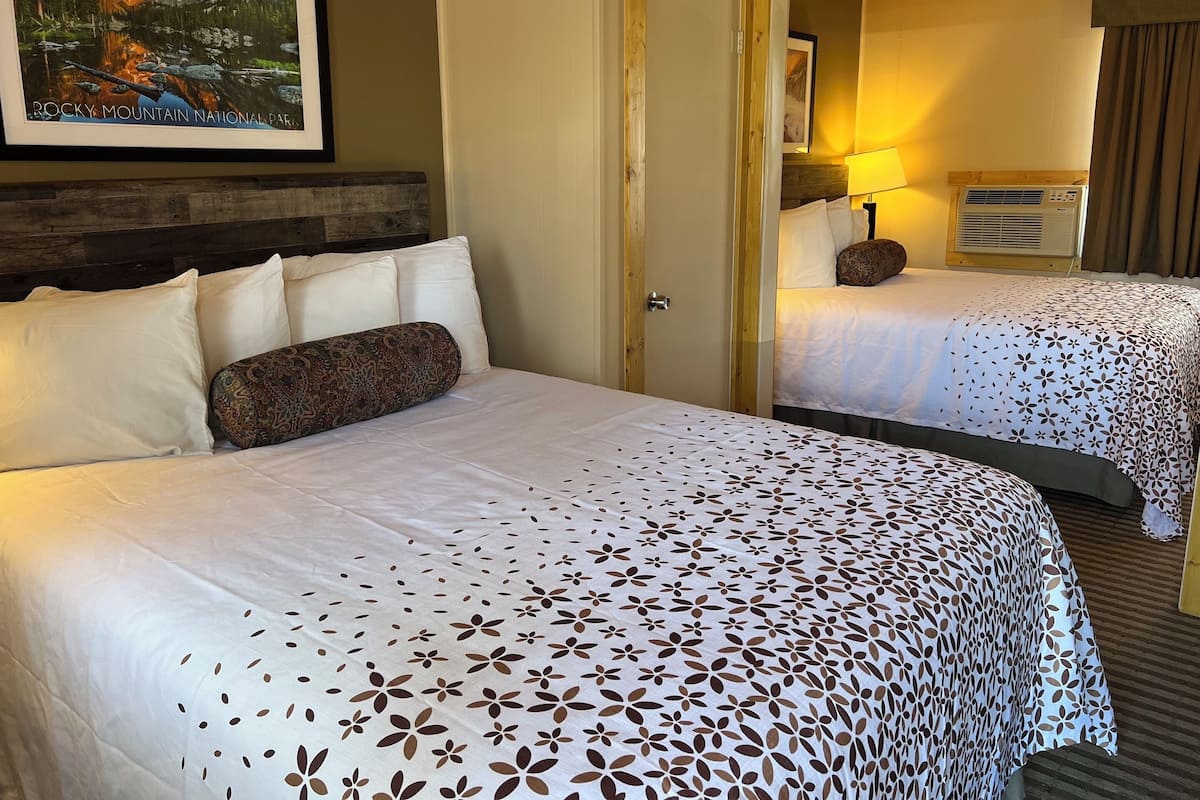 A hotel room with a large bed, a mirror, a nightstand, and a framed picture of a mountain landscape.