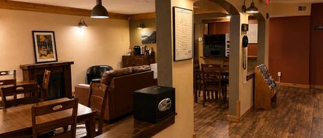A spacious living area with a fireplace, dining table, and seating. A kitchen with a microwave and a telephone is visible in the background.
