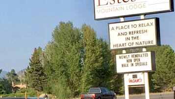 A sign for Estes Mountain Lodge advertising a place to relax and refresh in nature, with a newly renovated walk-in special.
