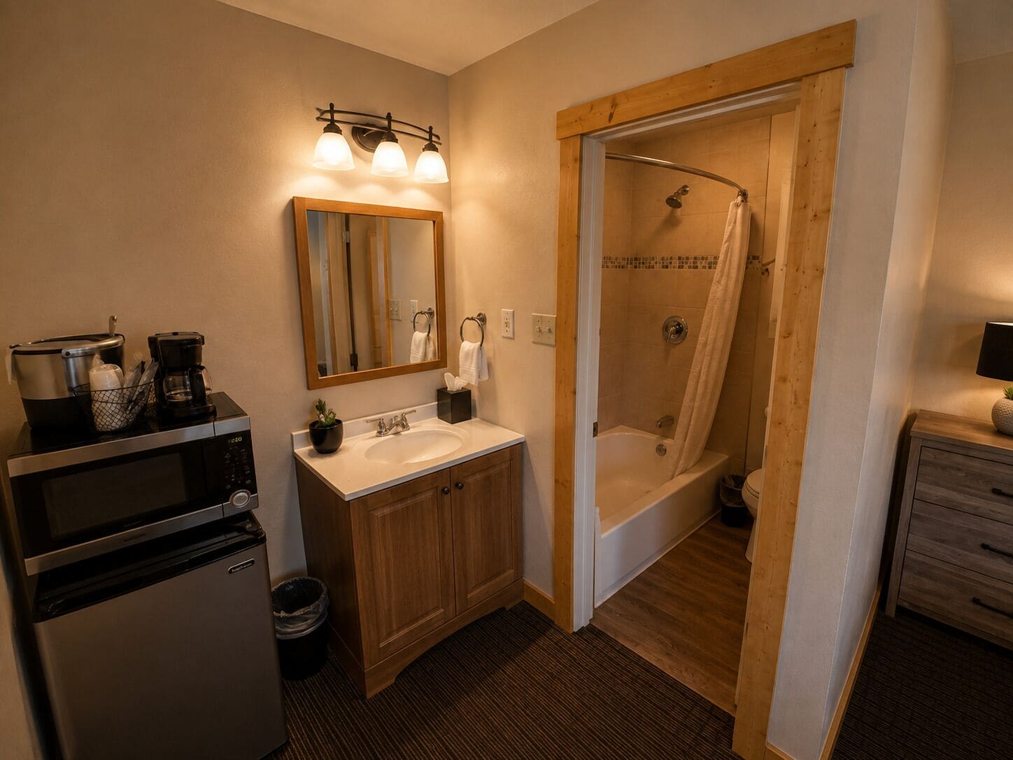 A bathroom with a sink, mirror, shower, and a microwave.