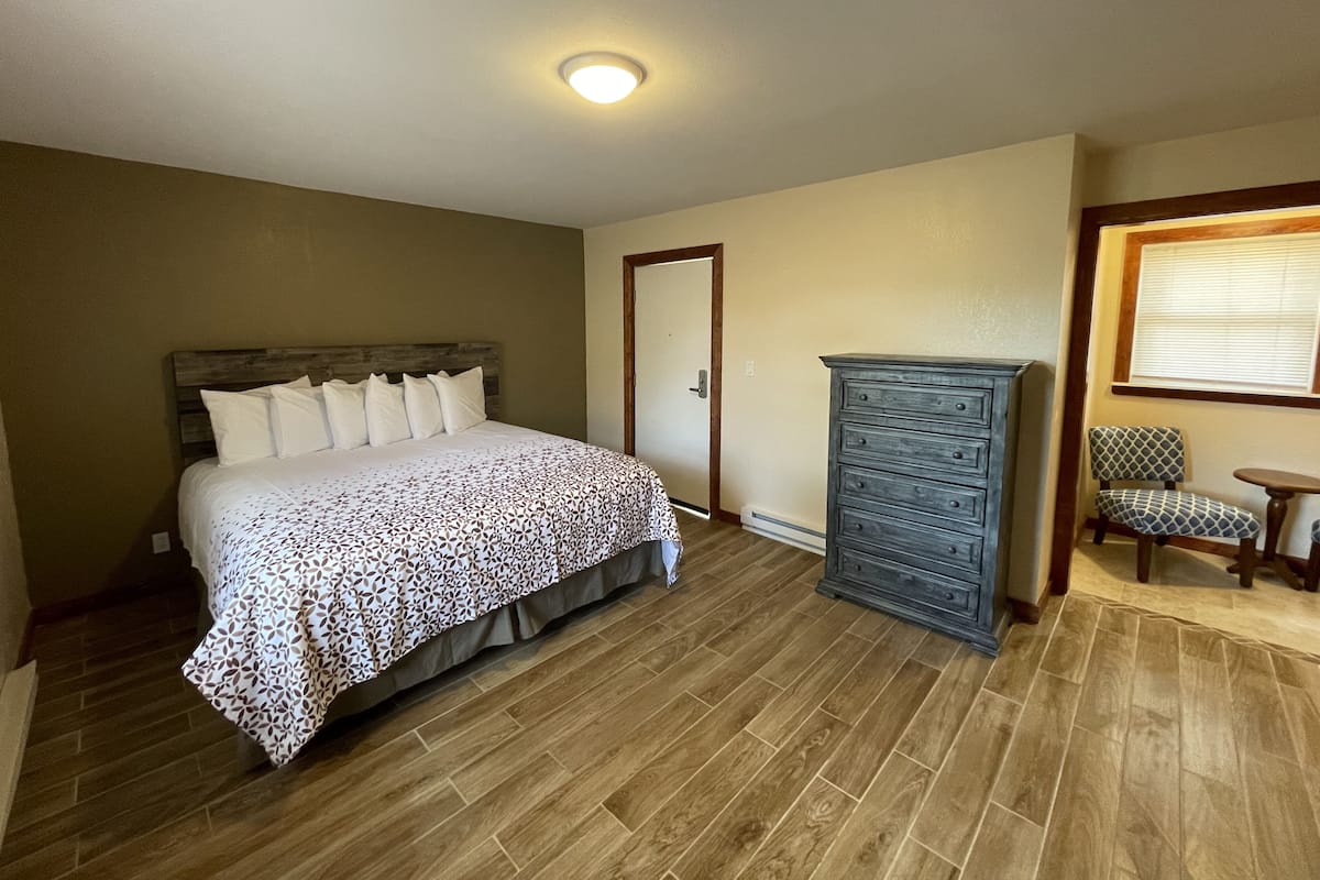 A bedroom with a bed, dresser, and chair.