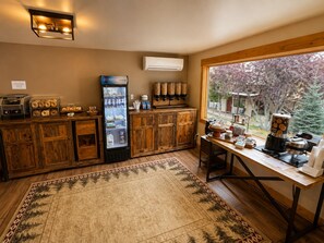 A kitchen area with a coffee machine, a refrigerator, and a window with a view of trees. - Estes Mountain Inn (Estes Park)