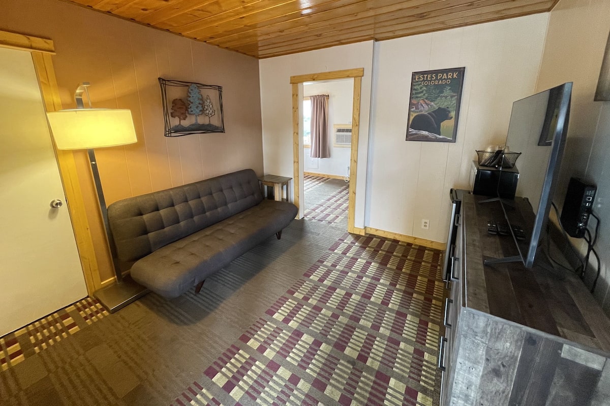 A room with a sofa, a lamp, a television, and a poster on the wall.