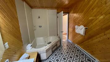A wooden cabin bathroom with a bathtub, a sink, and a shower.