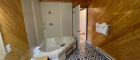 A wooden cabin bathroom with a bathtub, a sink, and a shower.