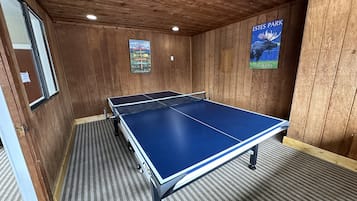 Una sala con pareti in legno e un tappeto a righe, con un tavolo da ping pong.