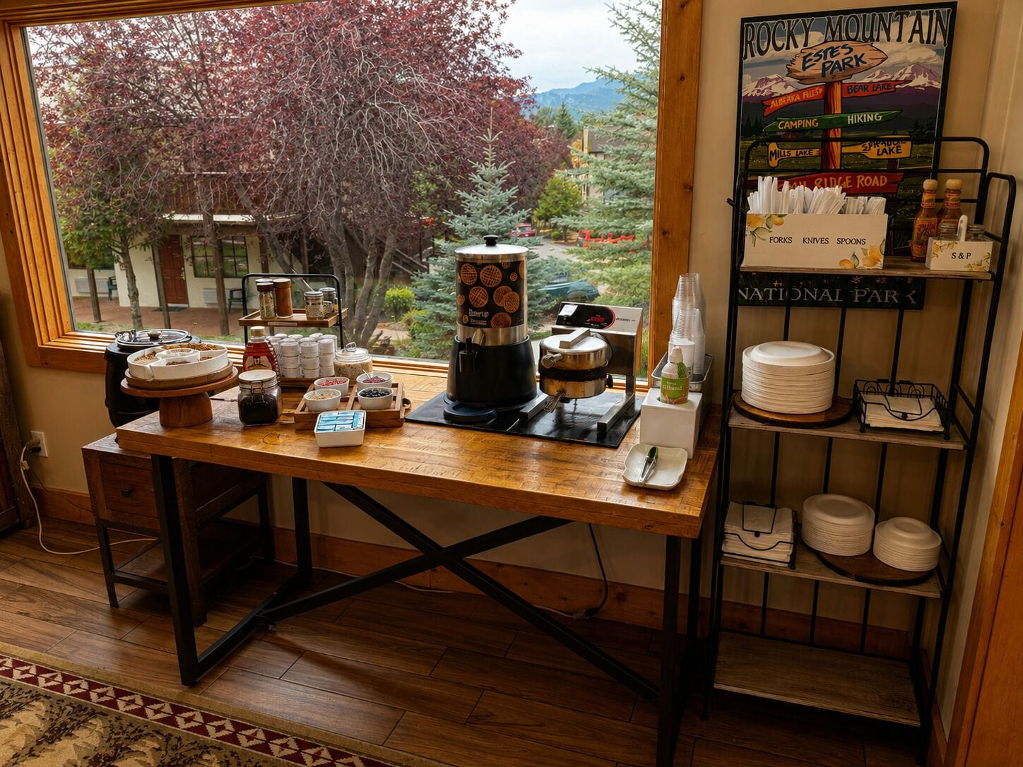 Morgenmadsbord med udsigt til Rocky Mountain National Park, en kaffemaskine og et udvalg af morgenmadsprodukter.