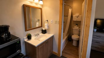 A modern bathroom with a wooden vanity, a sink, a mirror, and a shower area.