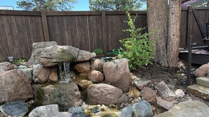 A rock garden with a small waterfall, surrounded by large rocks and a wooden fence in the background. - Estes Mountain Inn (Estes Park)