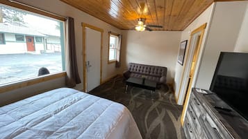 Une chambre d’hôtel avec un lit, un canapé, une télévision et une fenêtre avec des rideaux.