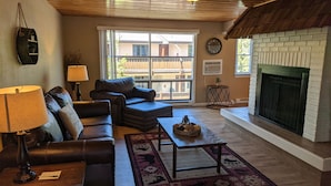 A living room with a fireplace, leather sofas, a coffee table, and a rug. - Estes Mountain Inn (Estes Park)