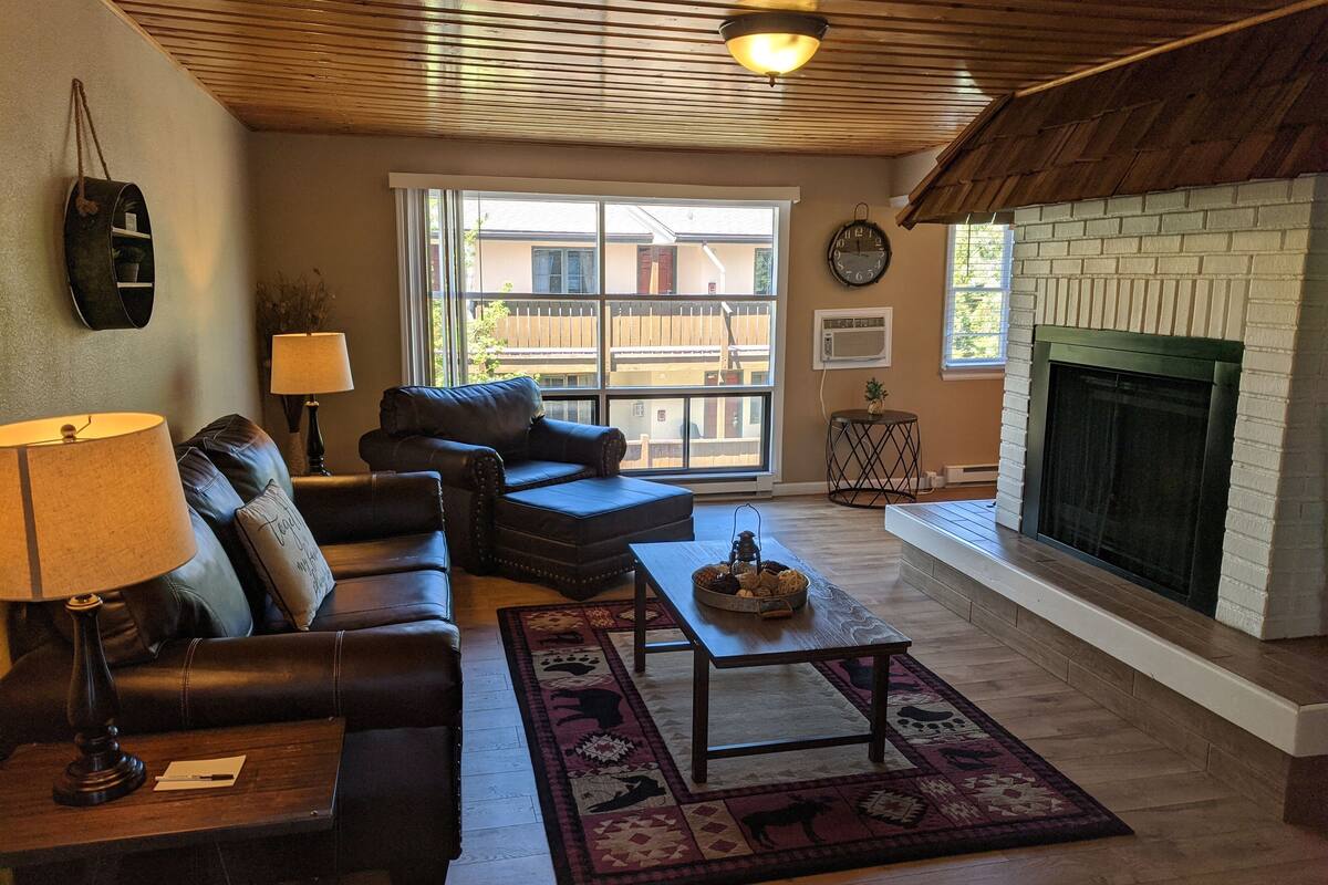A living room with a fireplace, leather sofas, a coffee table, and a rug.