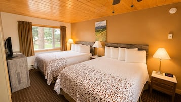 Habitación de hotel con dos camas, televisor, escritorio y ventana con cortinas.