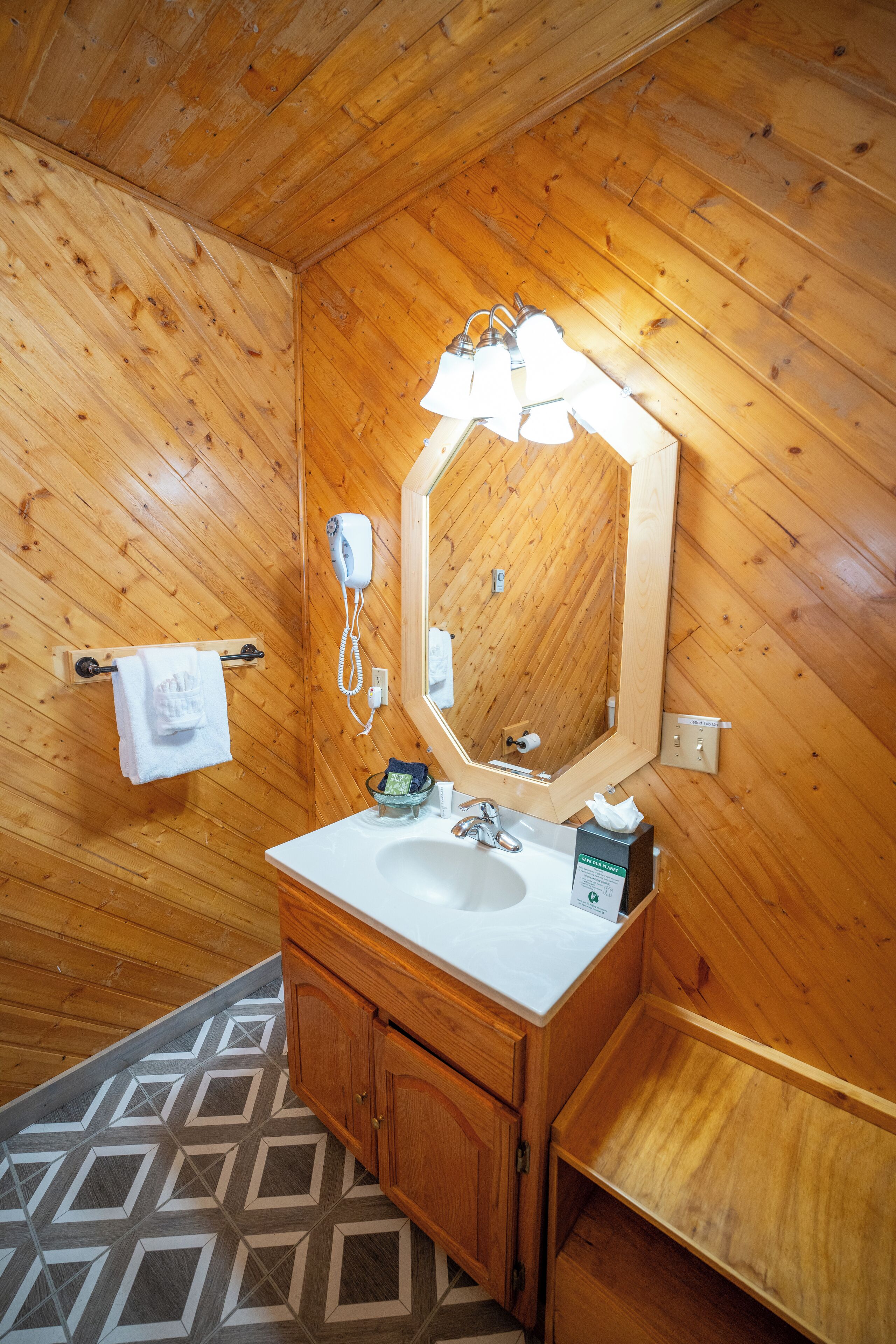 Une salle de bain aux murs lambrissés, avec un lavabo blanc, un miroir et un porte-serviettes.