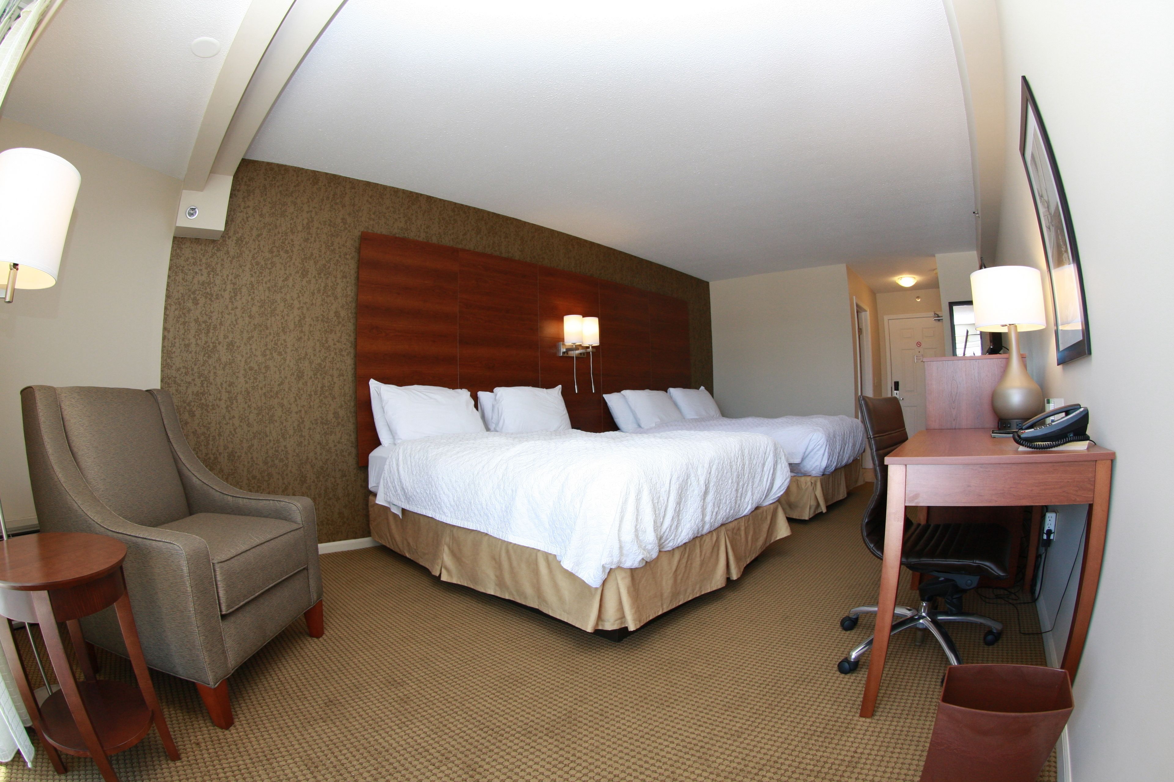 Une chambre d’hôtel avec un grand lit, une chaise, un bureau et une lampe.