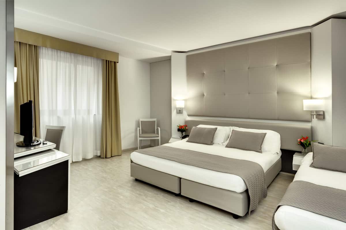 A modern hotel room with a large bed, a desk, and a TV.