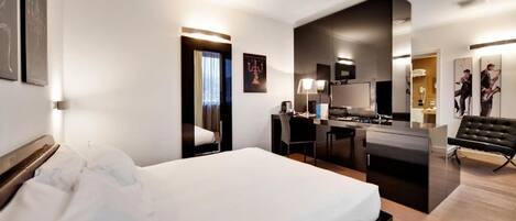 Habitación de hotel moderna con una cama grande, kitchenette, escritorio y zona de estar.